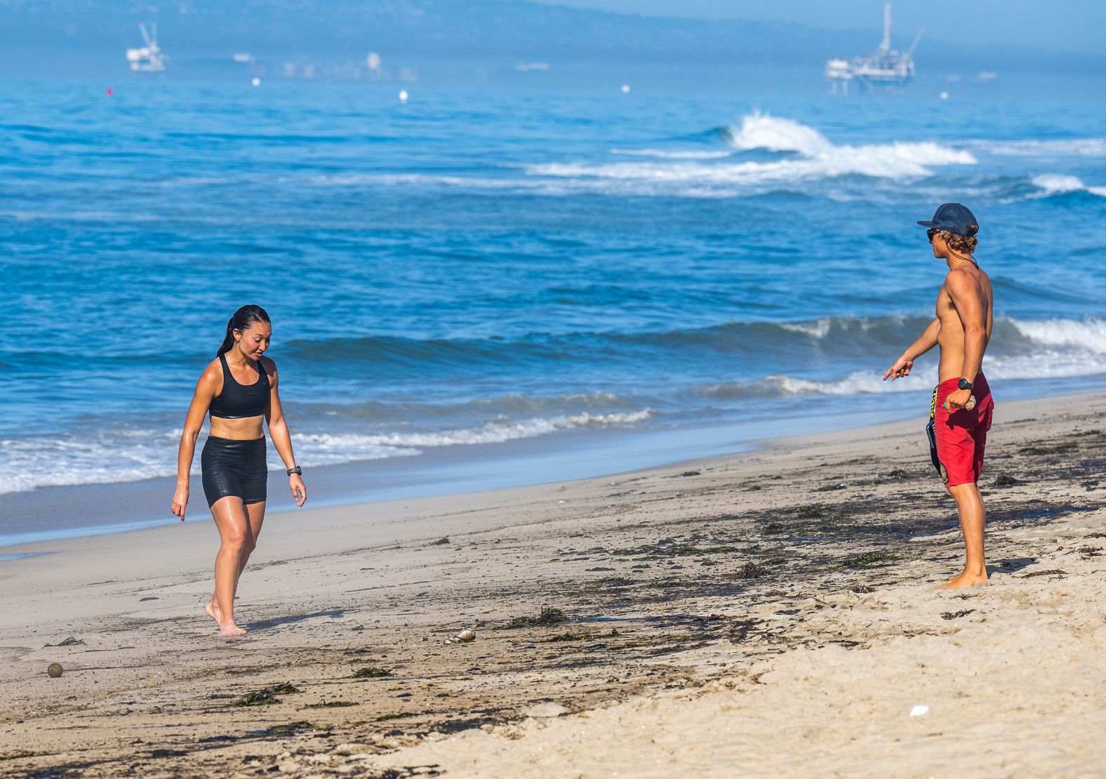 A Huntington Beach lifeguard points to the oil-soaked sand as he tells Melissa Panozzo to get out of the water on October 3. Panozzo hadn't heard the beaches had been closed, she said.