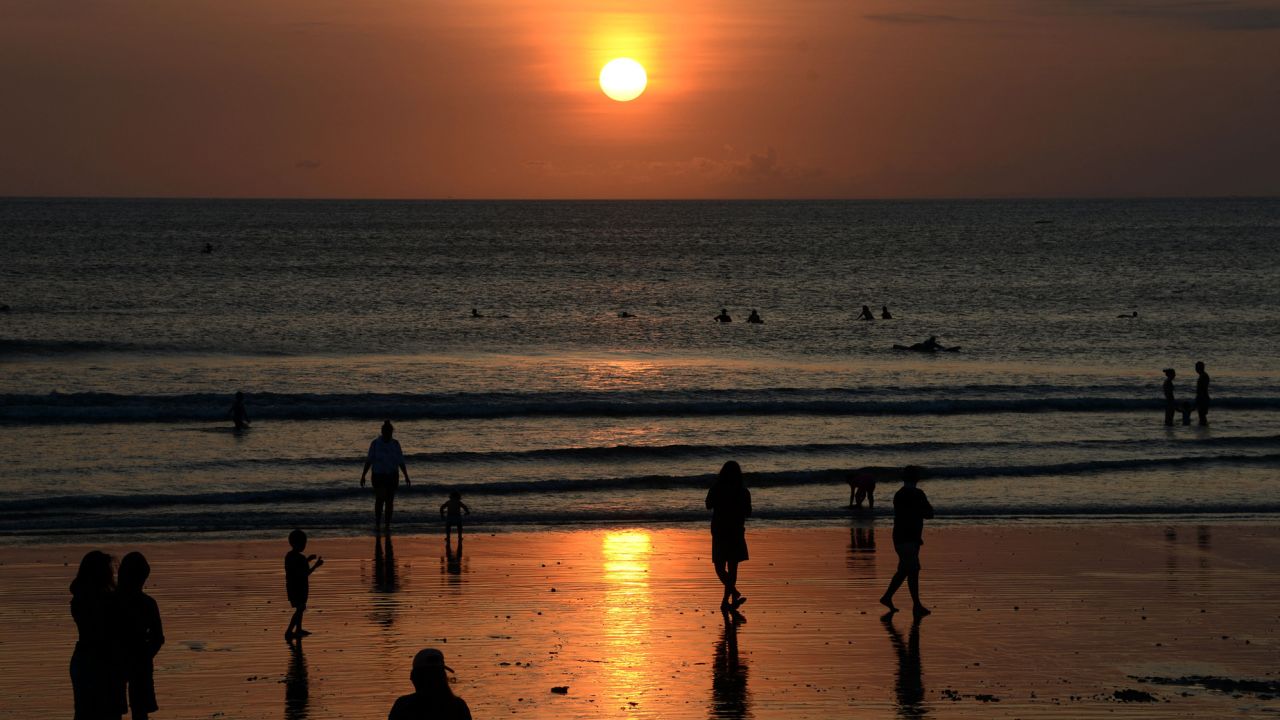 People visit Kuta beach during sunset near Denpasar on September 26, 2021. (Photo by SONNY TUMBELAKA / AFP) (Photo by SONNY TUMBELAKA/AFP via Getty Images)