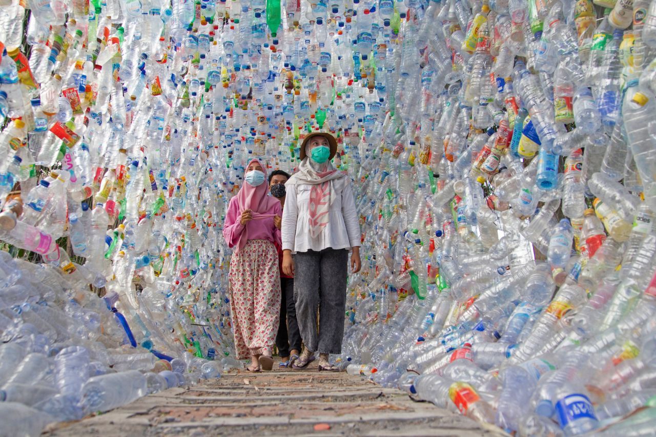 People walk through a tunnel built from plastic bottles collected from several rivers around the city.