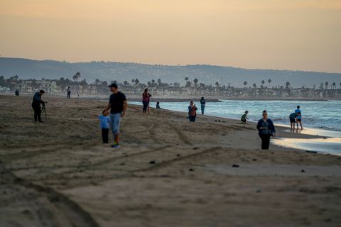Beachgoers walk along the coast of Huntington Beach on October 4.