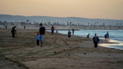 Beach goers wander the shore in the affected area off the coast of Huntington Beach.