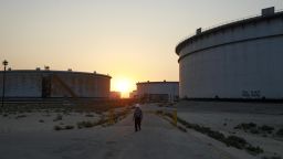 An employee walks past crude oil storage tanks at the Juaymah Tank Farm in Saudi Aramco's Ras Tanura oil refinery and oil terminal in Ras Tanura, Saudi Arabia, on Oct. 1, 2018. Saudi Arabia is seeking to transform its crude-dependent economy by developing new industries, and is pushing into petrochemicals as a way to earn more from its energy deposits.