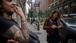 A woman checks her Instagram account as she stands on a street with her friend, in New York city on October 4, 2021. - Facebook and its Instagram and WhatsApp platforms were hit by a massive outage, impacting potentially tens of millions of people as users flocked to other networks to sound off. 