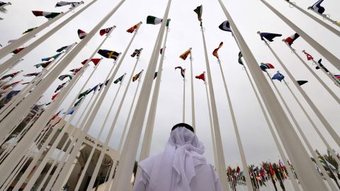 An Emirati visitor stands beneath the waving flags of countries participating in the Expo 2020 in the Gulf Emirate of Dubai on October 6, 2021. 