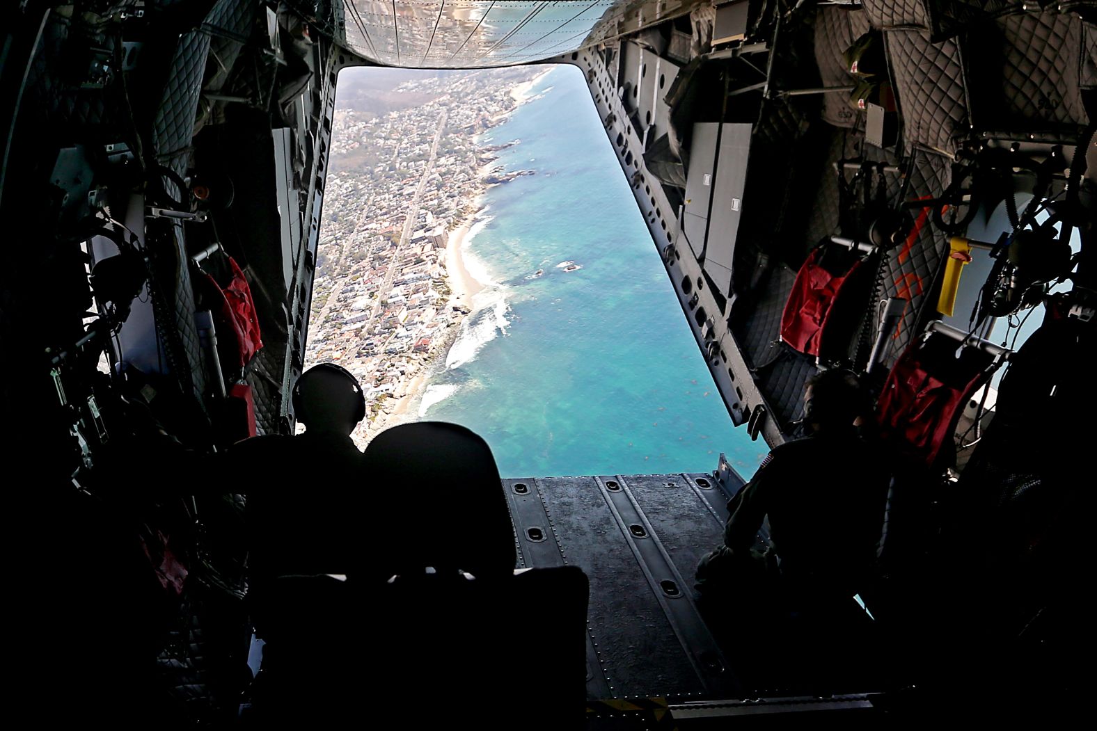 Members of a Coast Guard flight crew look out over the Orange County coastline as they search for oil in the water on Tuesday, October 5.