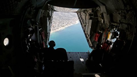 Members of a Coast Guard flight crew look out over the Orange County coastline as they search for oil in the water on October 5.