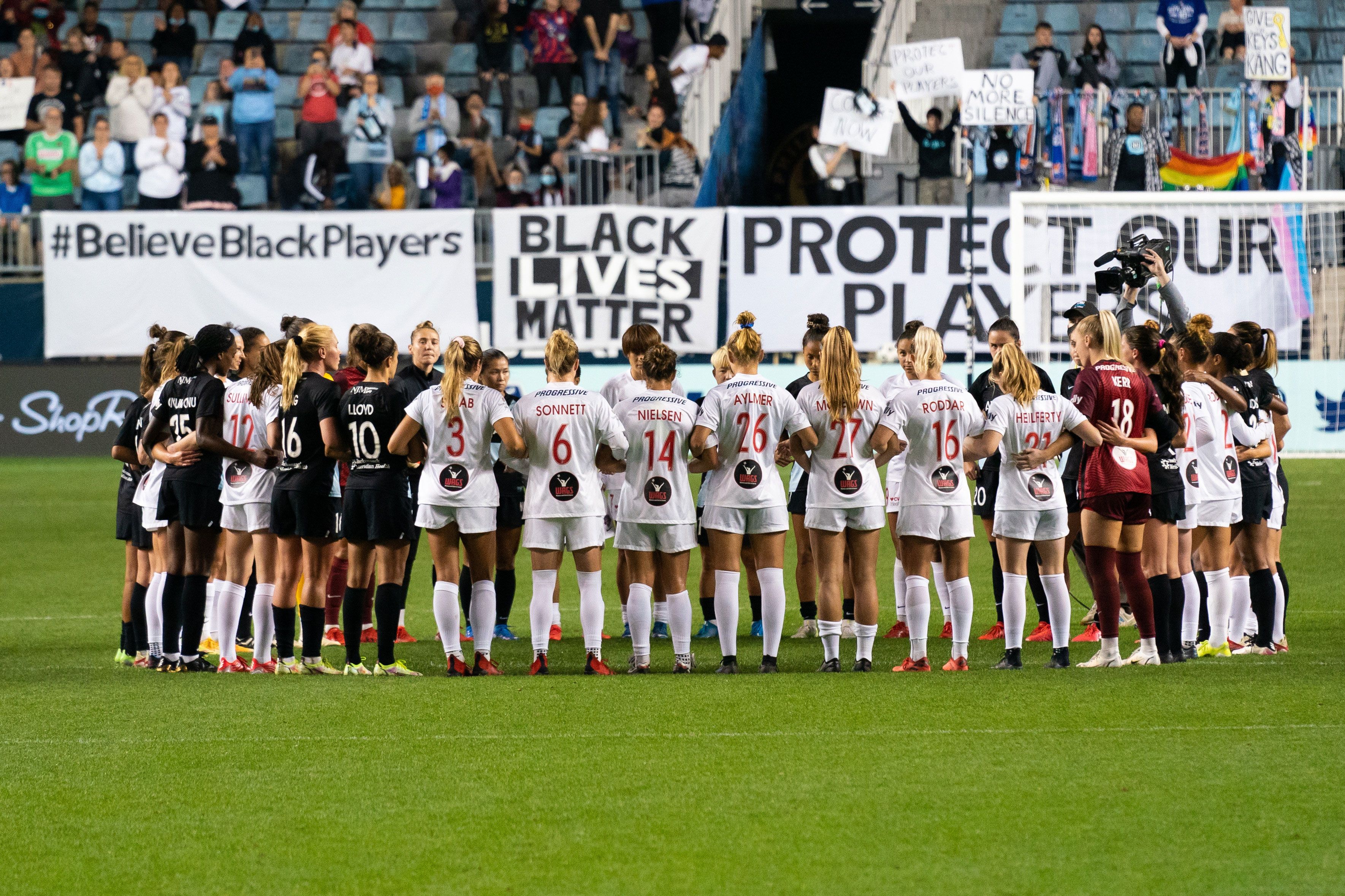 National Women's Soccer League players pause mid-match, stand in