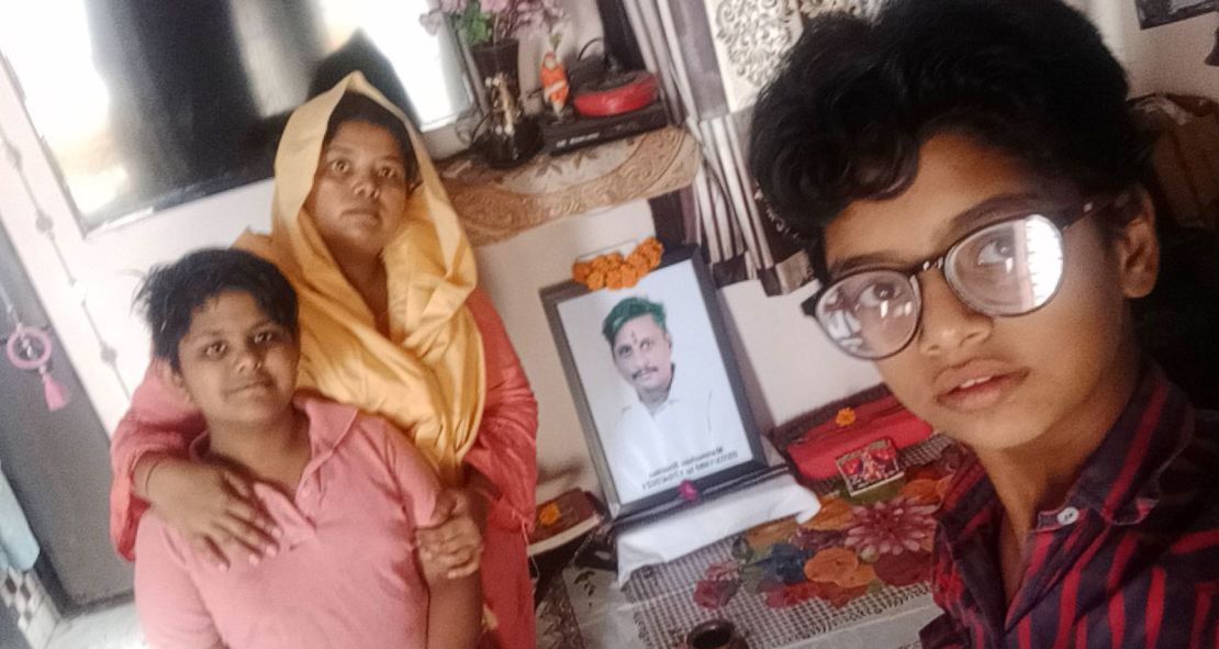 Pooja Sharma and her children at home in front of a photo of her late husband, who died of Covid-19 in April in Delhi, India.