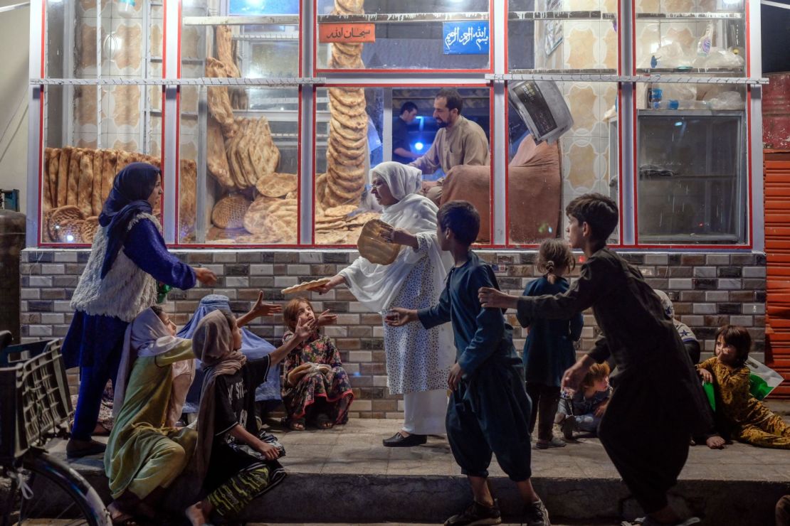 A woman gives bread to young people in need in front of bakery in Kabul on September 19, 2021. 