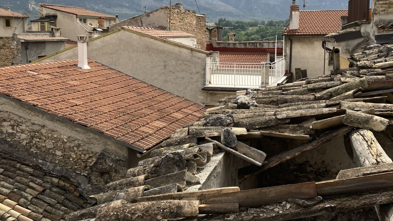 Some houses have collapsed roofs. Others are still intact.