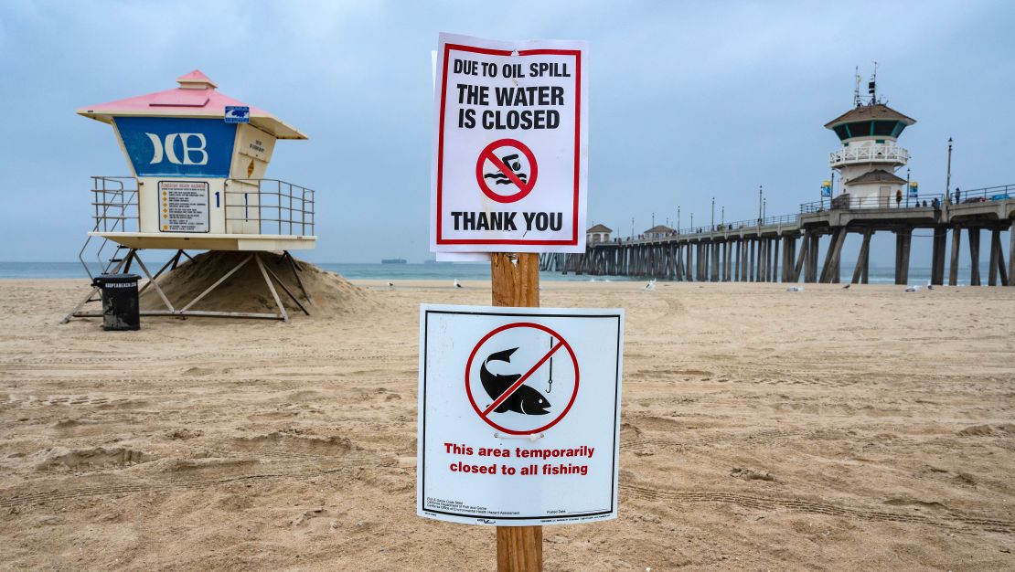 A sign posted in the sand just south of the Huntington Beach Pier lets beach goers know that the shoreline and water are closed due to the offshore oil spill last weekend.