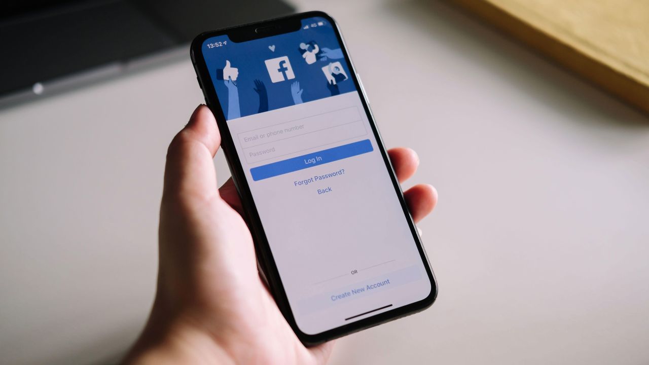 A woman's hand holding an iPhone X to use facebook with login screen. Facebook is a largest social network and most popular social networking site in the world.