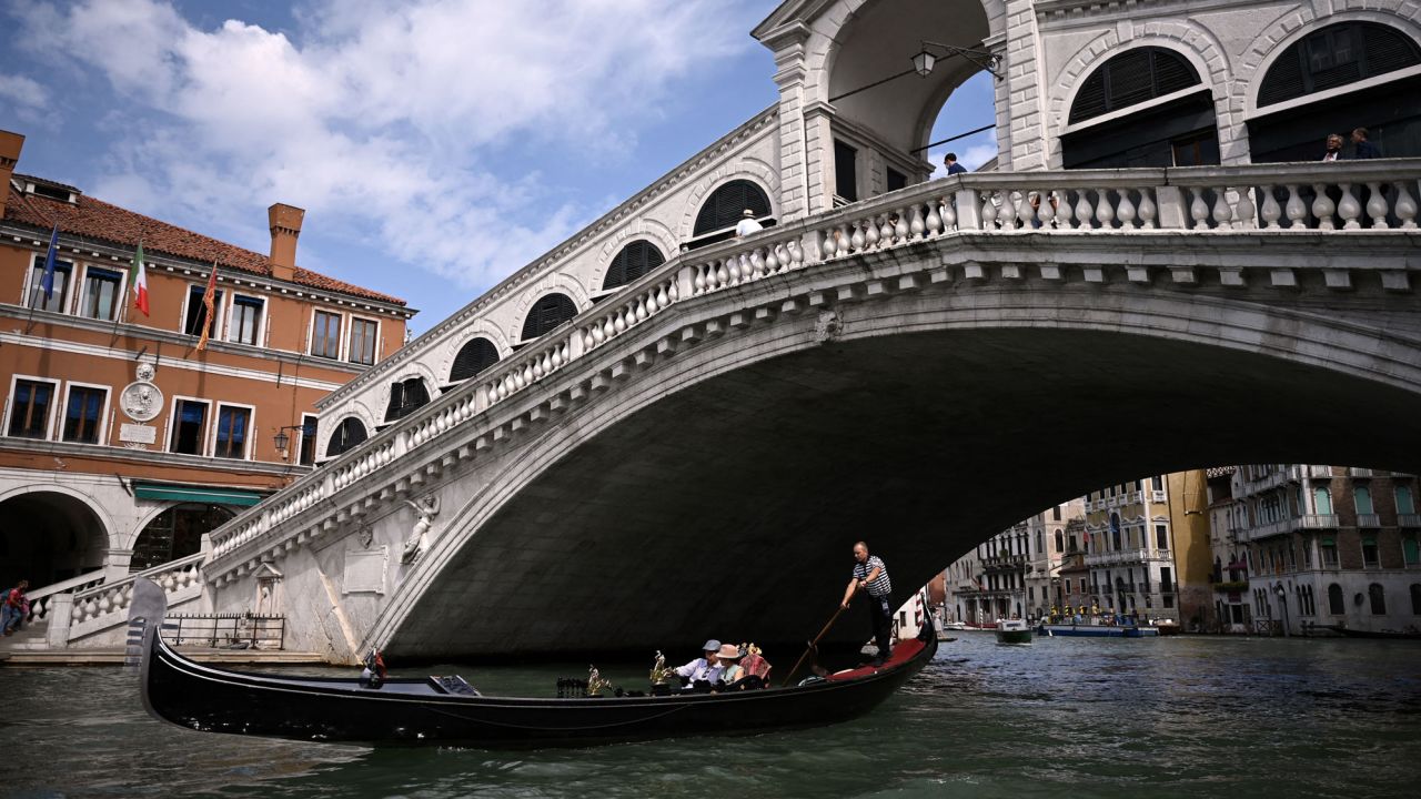Tourists go for a gondola ride by the 16th-century stone arch Rialto Bridge at the Grand Canal in Venice on September 7, 2021