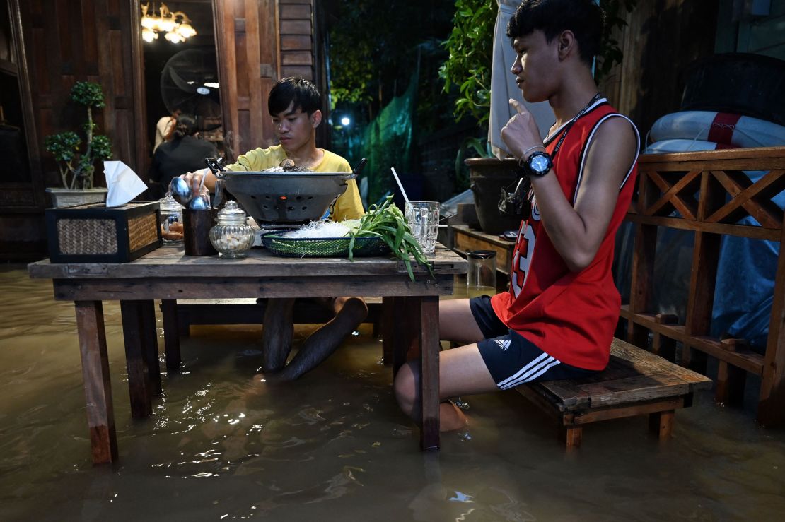 People enjoy dinner at the Chaopraya Antique Cafe, as flood water from the Chao Phraya river surges into the restaurant.