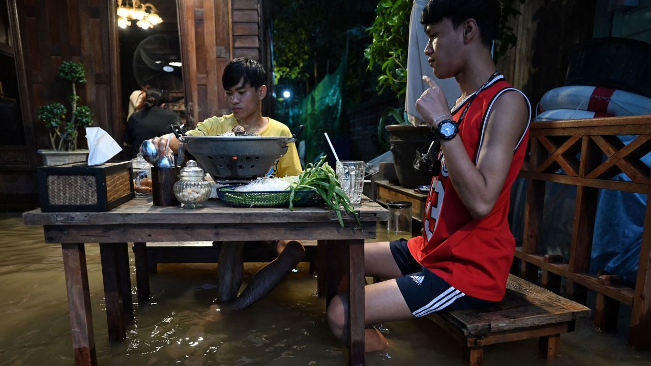 People enjoy dinner at the Chaopraya Antique Cafe, as flood water from the Chao Phraya river surges into the restaurant.