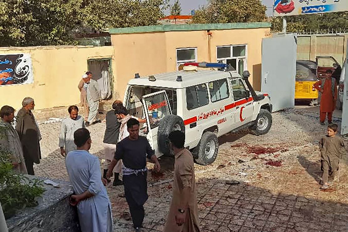 Afghan men stand next to an ambulance after an attack on a Shia mosque in Kunduz.