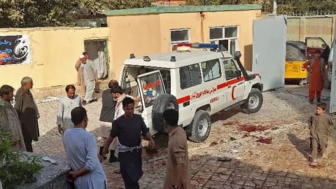 Afghan men stand next to an ambulance after an attack on a Shia mosque in Kunduz.