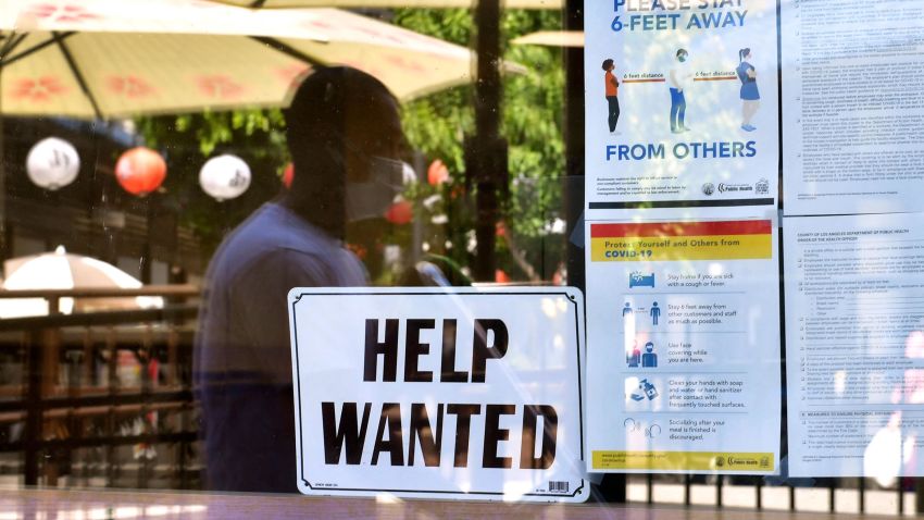 A 'Help Wanted' sign is posted beside Coronavirus safety guidelines in front of a restaurant in Los Angeles, California on May 28, 2021.