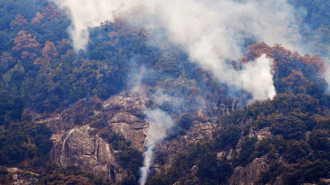 Smoke rises from a mountainside adjacent to Moro Rock during a tour of the KNP Complex Fire burn area in Sequoia National Park, California.