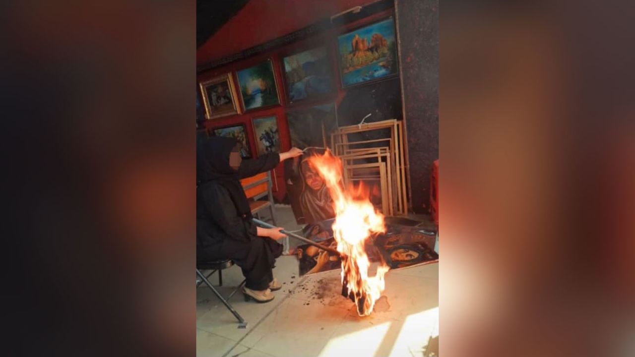 An Afghan artist burns her artwork at a studio days after the Taliban takeover of the country. Part of this image has been blurred by CNN for safety reasons.