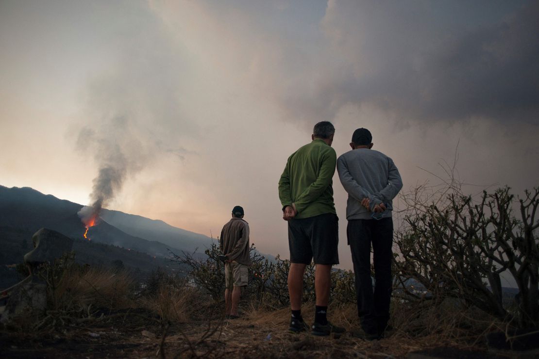 People watch as the  volcano spews lava, ash and smoke on October 10.