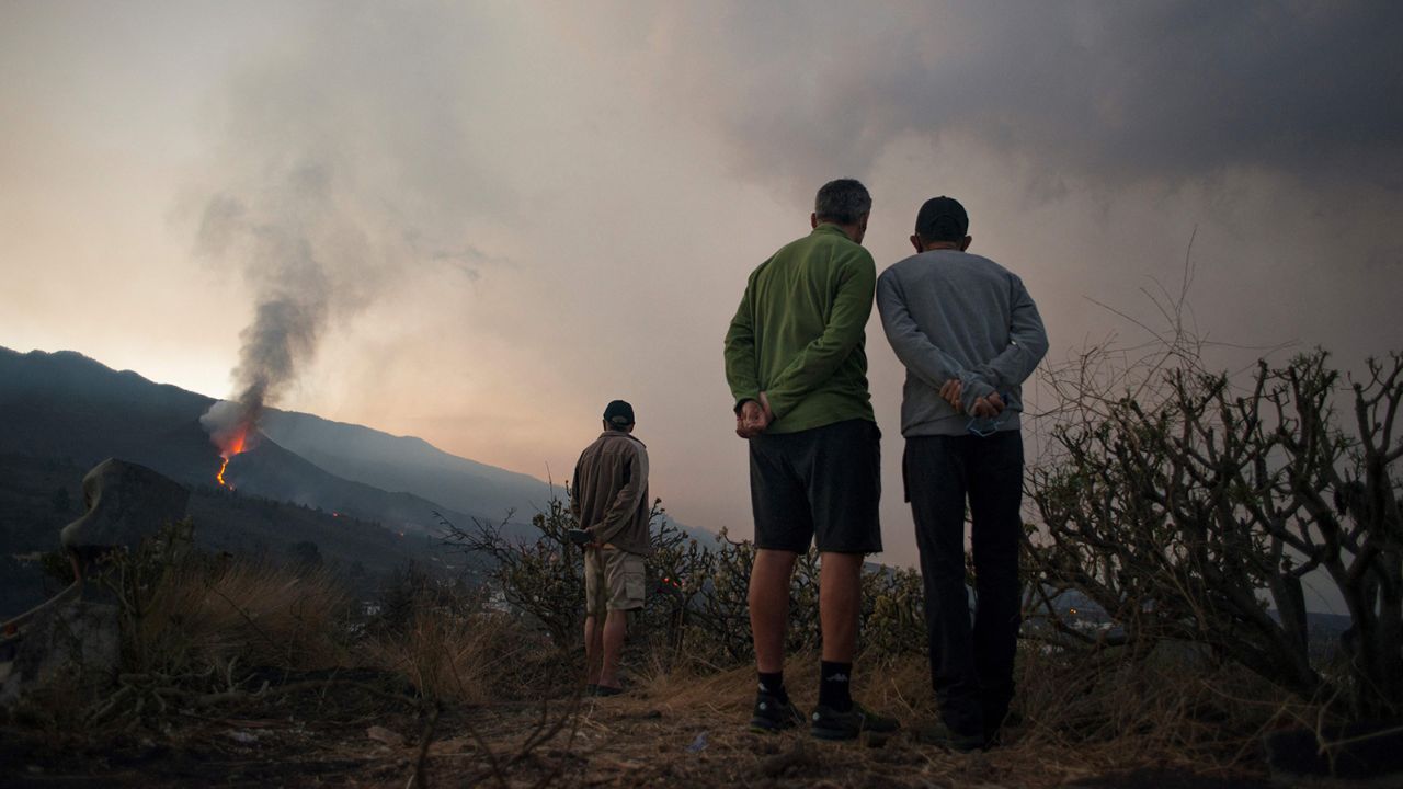 People watch as the  volcano spews lava, ash and smoke on October 10.