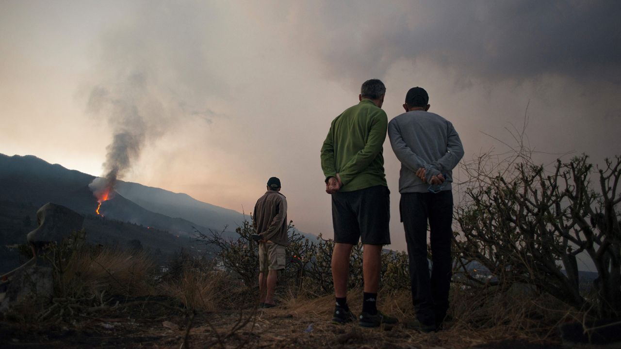 People watch as the volcano spews lava, ash and smoke on October 10.