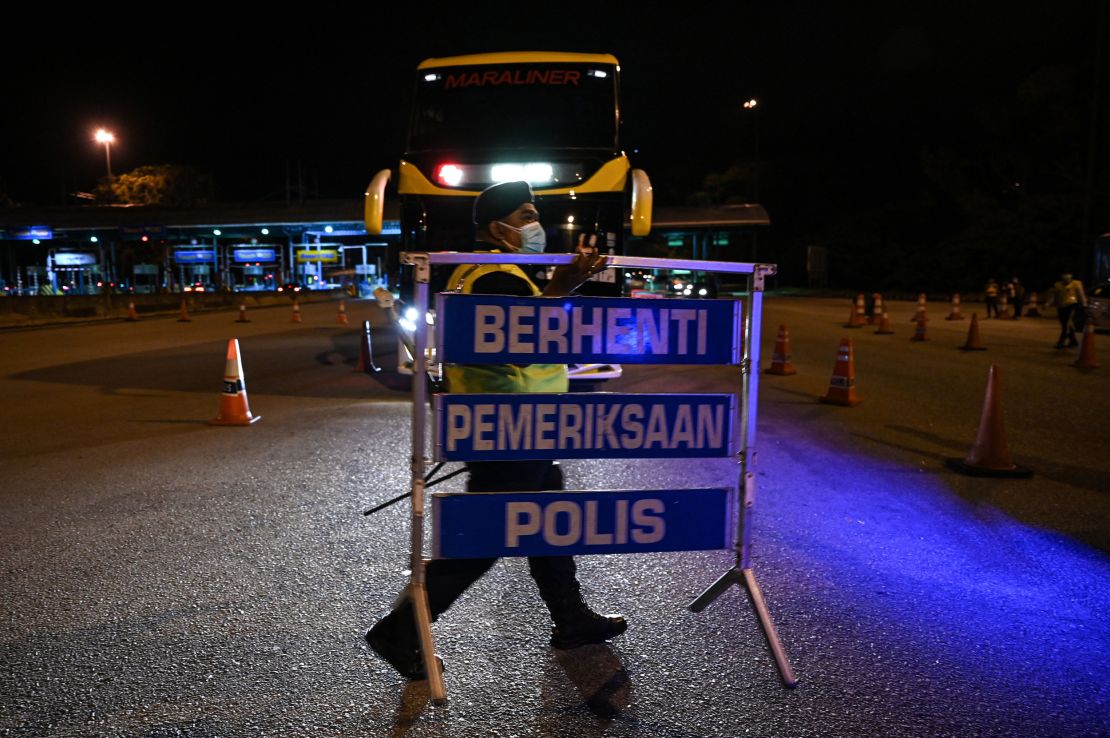 A police officer removes a barricade at a roadblock after the end of a partial lockdown in Bentong, Malaysia's Pahang state on October 11.