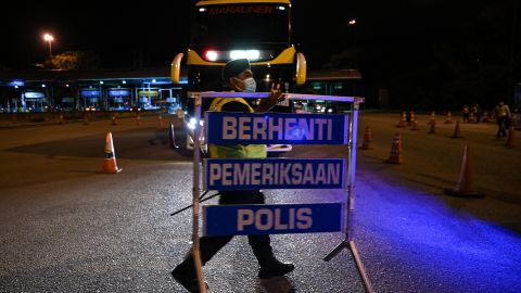 A police officer removes a barricade at a roadblock after the end of a partial lockdown in Bentong, Malaysia's Pahang state on October 11.