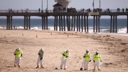 Cleanup workers at a mostly empty Huntington Beach about one week after an oil spill from an offshore oil pipeline. 