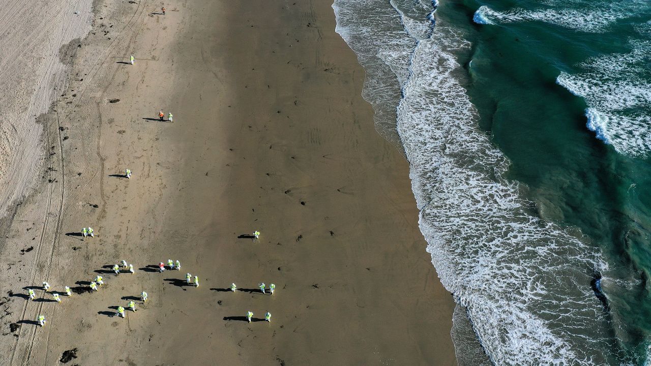 Cleanup workers scour the sand in Huntington Beach, California, after an oil spill from a pipeline leak. 