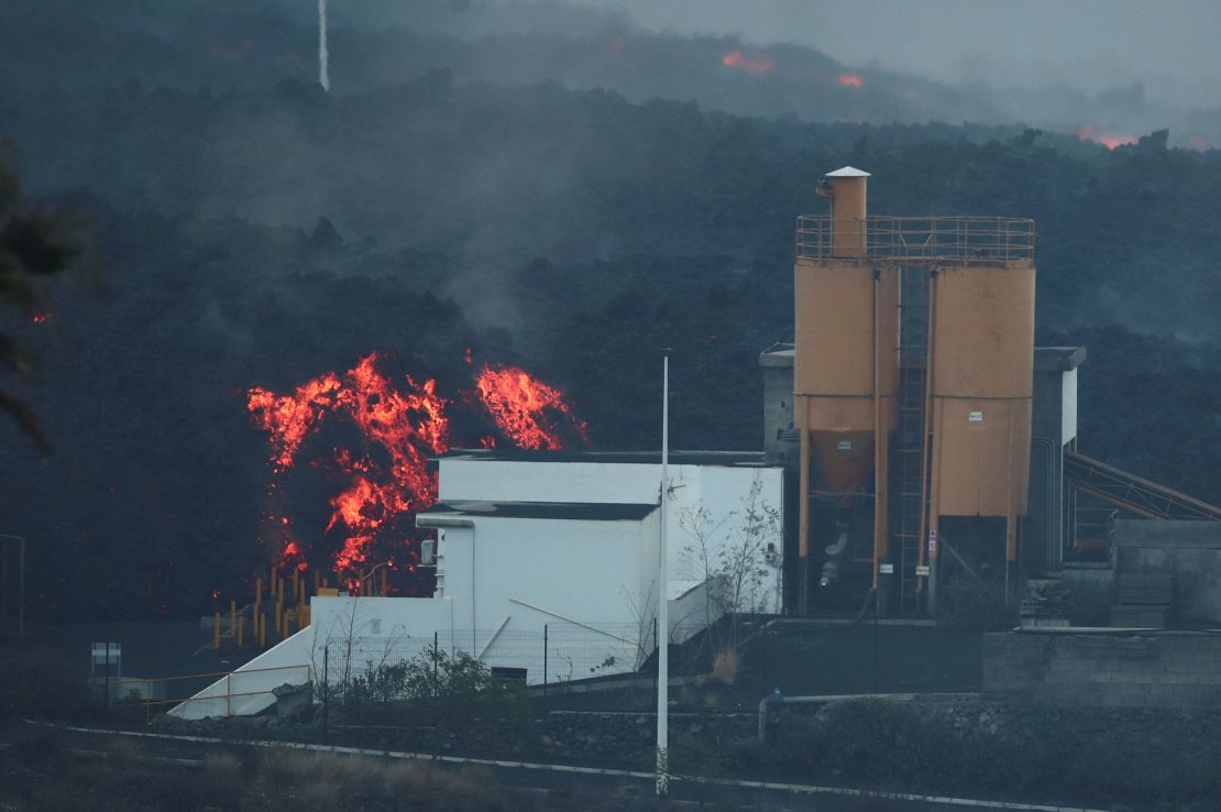 Lava rolls down behind a cement factory earlier this month as the Cumbre Vieja volcano continues to erupt on La Palma.