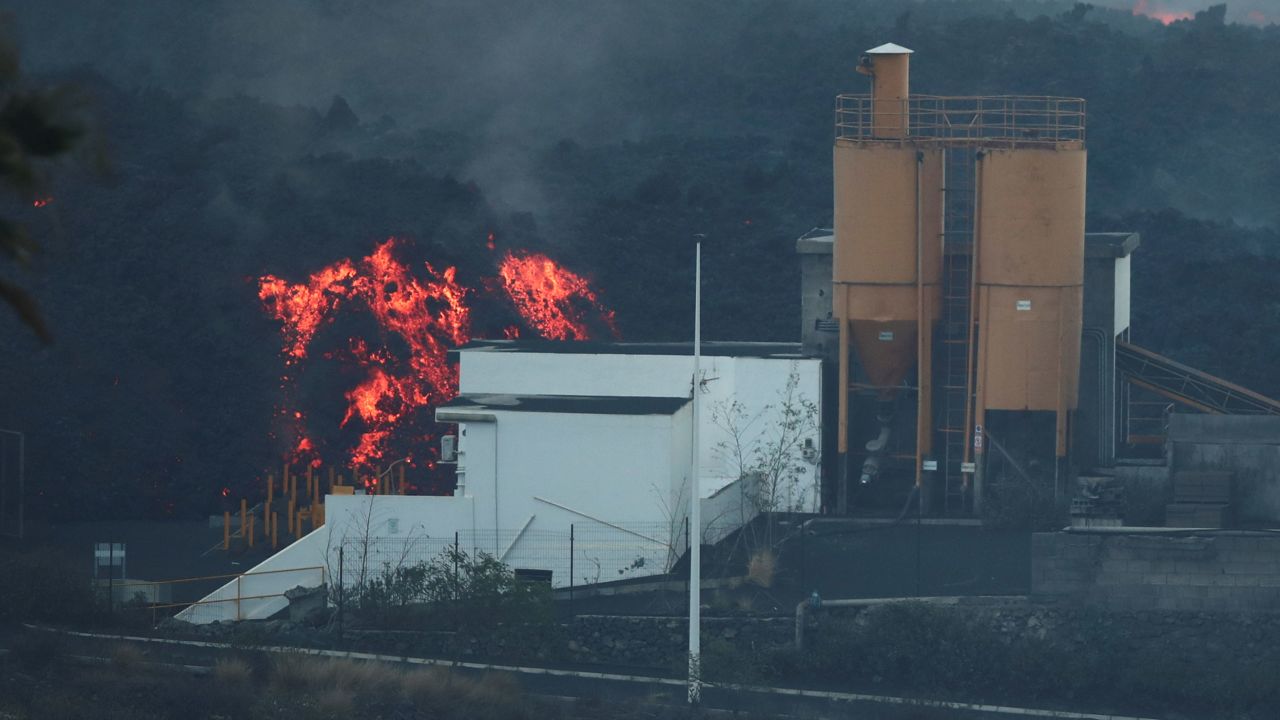 Lava rolls down behind a cement factory earlier this month as the Cumbre Vieja volcano continues to erupt on La Palma.