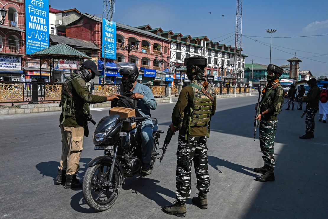 Security personnel check the bag of a motorist along a street in Srinagar on October 9.