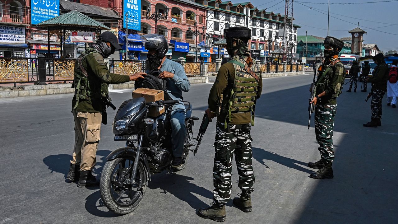 Security personnel check the bag of a motorist along a street in Srinagar on October 9.