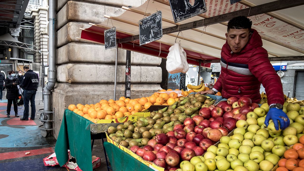 A man arranges apples on his fruit stall at the Barbes market in Paris on March 18, 2020.