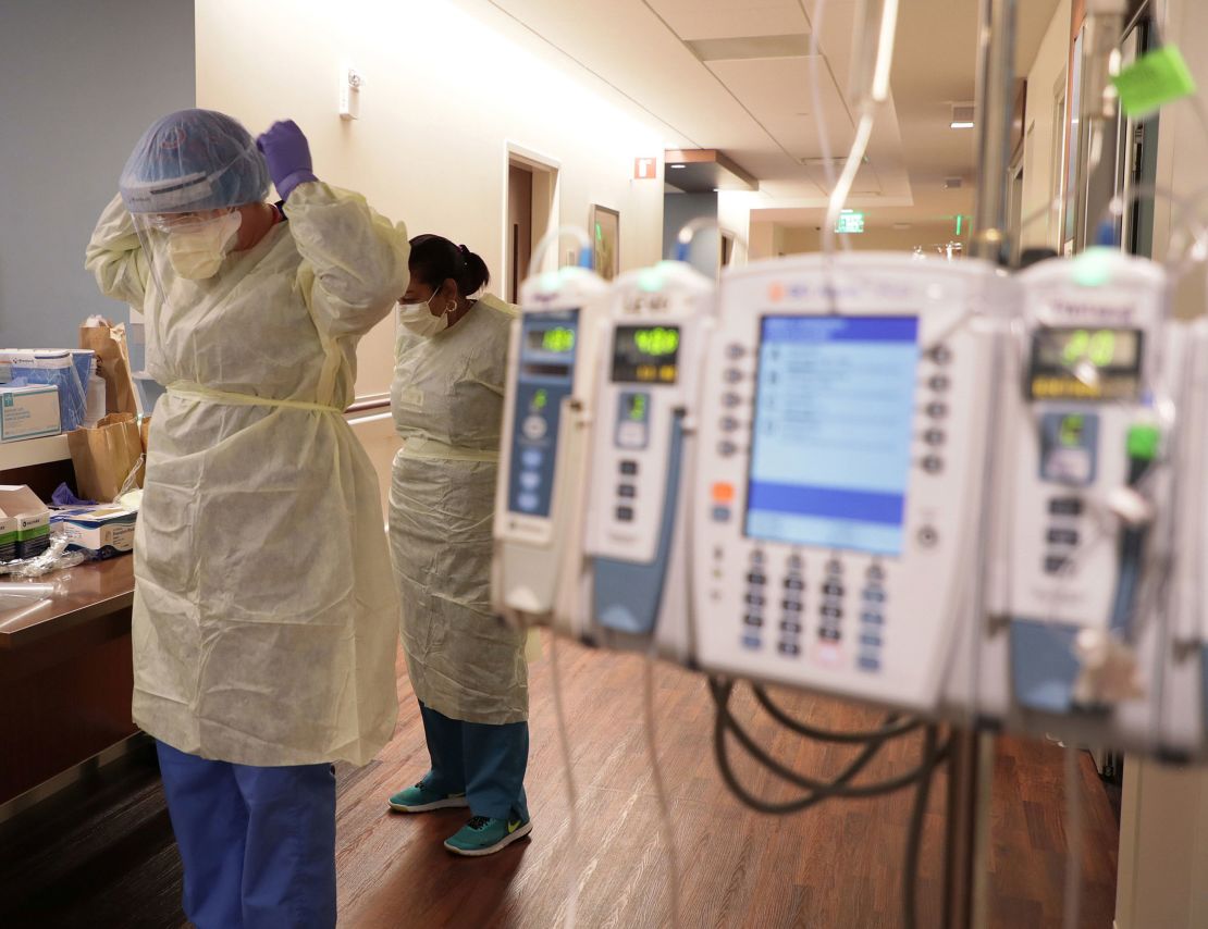 Hospital staff don personal protective equipment before entering the room of a Covid-19 patient at the Northwestern Medicine Lake Forest Hospital ICU in Illinois.