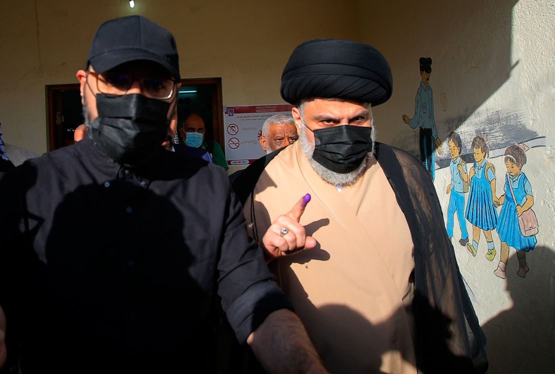 Populist Shia cleric Muqtada al-Sadr displays his ink-stained finger that shows he voted, at a polling center during the parliamentary elections in Najaf, Iraq, Sunday, Oct. 10, 2021.
