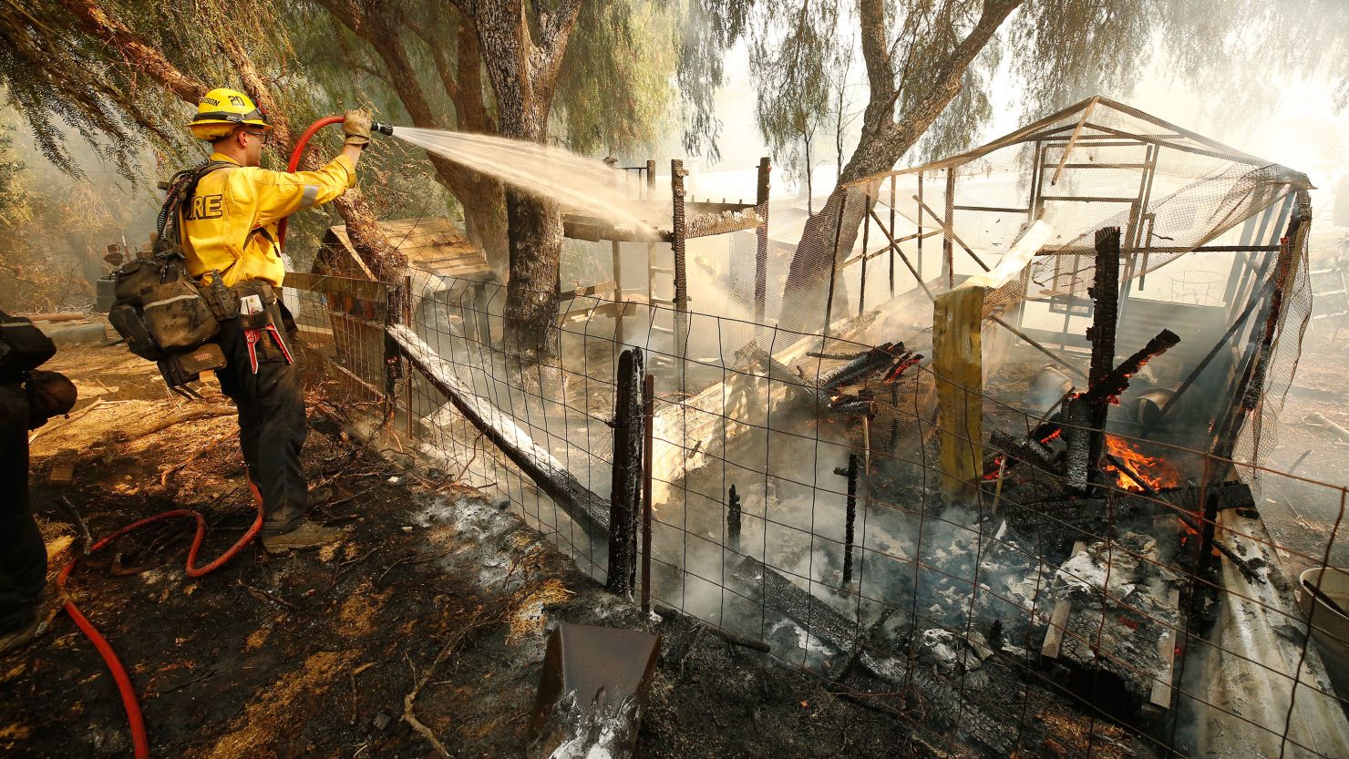 A Cal Fire Firefghter puts out flames from the Alisal Fire in an animal pen near a home along Refugio Road in Gaviota Coast, California, on Tuesday.