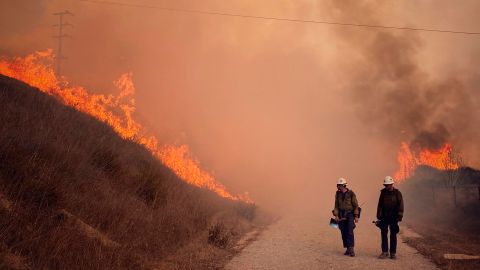 Santa Barbara County Fire Hand Crew members fight fire with fire and burn off pockets of grass along northbound Highway 101 north of Arroyo Hondo Canyon in Santa Barbara County, California, Tuesday.