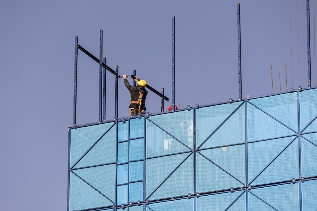 A worker installing safety netting at an apartment block under construction in the Nanchuan area of Xining, Qinghai province, China, on Sept. 28, 2021. 