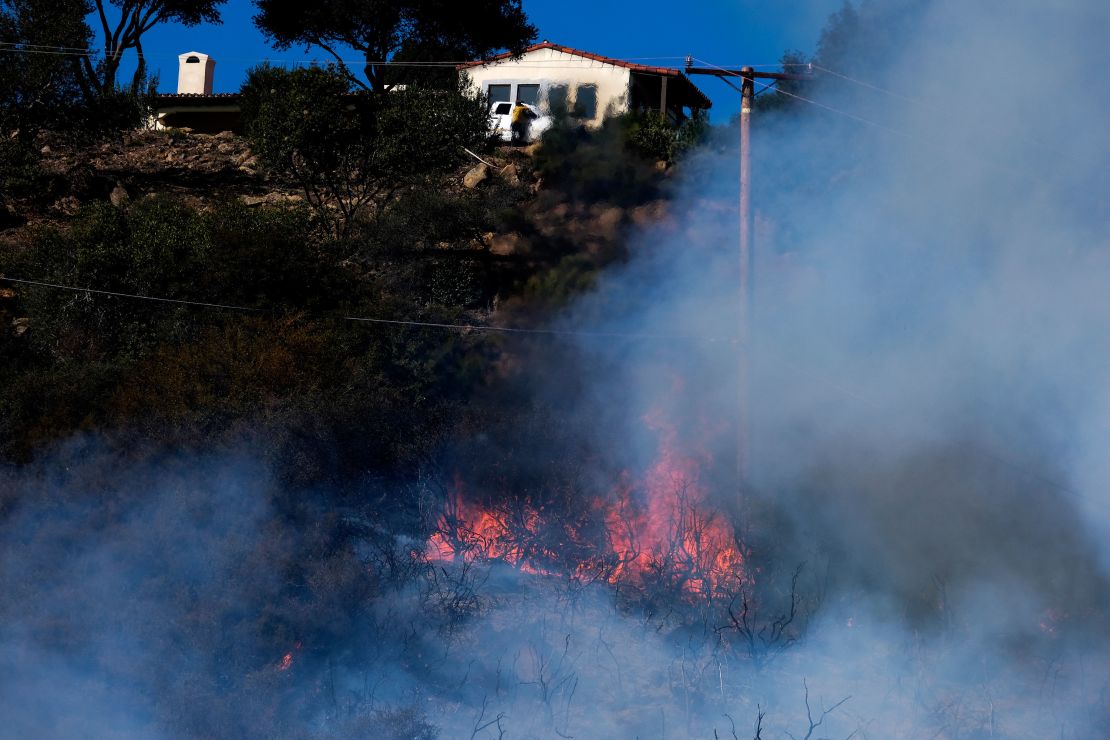 A wildfire raging through Southern California's coastal mountains threatened ranches and rural homes and kept a major highway shut down Wednesday.