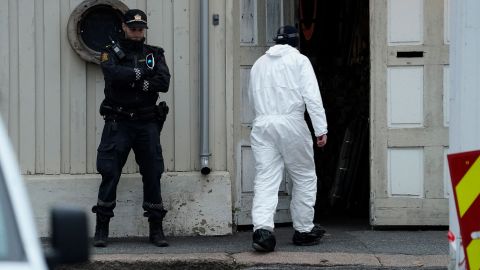 A police investigator passes a Norwegian policeman standing guard Thursday as investigations continue into the deadly bow-and-arrow attack in Kongsberg, Norway.