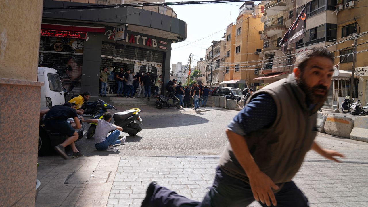 A man runs to take cover as supporters of a Shiite group allied with Hezbollah fire weapons during armed clashes that erupted during a protest in the southern Beirut suburb of Dahiyeh, Lebanon, Thursday, Oct. 14, 2021. It was not immediately clear what triggered the gunfire, but tensions were high along a former civil war front-line between Muslim Shiite and Christian areas. (AP Photo/Hassan Ammar)