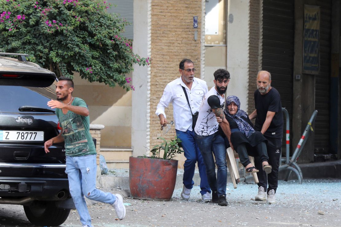 Men help evacuate an elderly woman after gunfire erupted, in Beirut, Lebanon October 14, 2021.