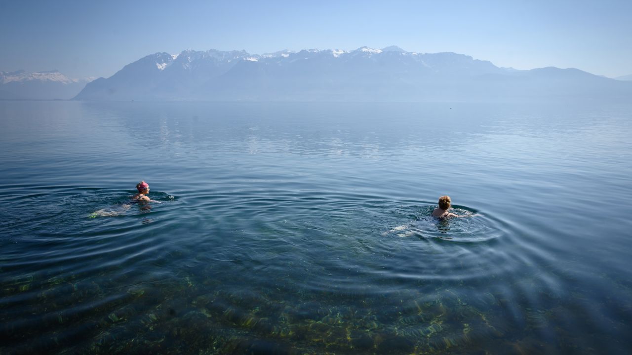 TOPSHOT - Two women swim in Lake Geneva with a temperature of 8 degree Celsius (46.4 Fahrenheit), as the country remains in lockdown to curb the spread of the novel corona virus, COVID-19, in Cully on April 4, 2020. - Switzerland on April 4, 2020 saw the number of cases of the new coronavirus in the country pass 20,000, as its death toll in the pandemic swelled to pass 500. (Photo by Fabrice COFFRINI / AFP) (Photo by FABRICE COFFRINI/AFP via Getty Images)
