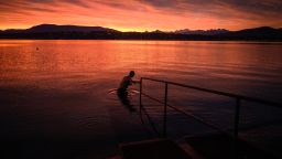 A man wades into Lake Geneva for a sunrise swim on October 20, 2020 in Geneva. (Photo by Fabrice COFFRINI / AFP) (Photo by FABRICE COFFRINI/AFP via Getty Images)