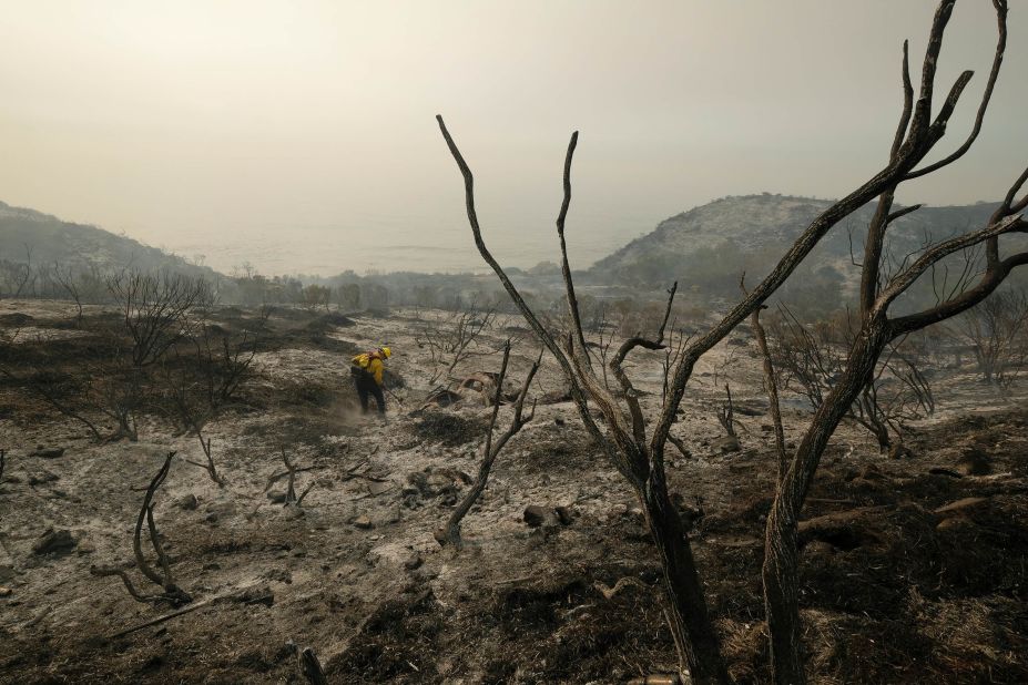 A firefighter puts out a roadside fire in Goleta, California, on Wednesday, October 13.