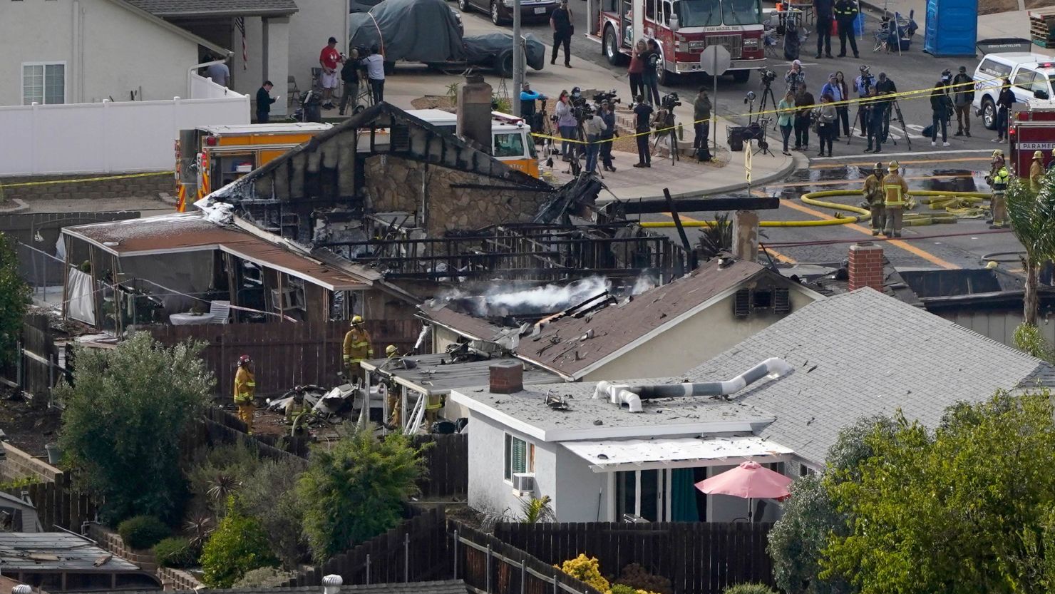 Emergency crews work the scene of a small plane crash in Santee, Calif., that killed two people, injured two others and set two homes ablaze.