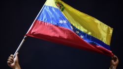 A man displays a Venezuelan flag as relatives and friends of 28 Venezuelan migrants who died when a boat transporting them to Trinidad and Tobago sank, protest in Guiria, Venezuela, on December 18, 2020. - At least 28 Venezuelan migrants died when a boat heading for Trinidad and Tobago sank, Attorney General Tarek William Saab said on Thursday. Between 2018 and 2019 around 100 people disappeared while trying to make the perilous 100-kilometre (60-mile) journey from the northeastern port of Guiria to Trinidad. Venezuela is in the midst of economic and political crises, suffering three years of hyperinflation and a seven-year recession. (Photo by Yuri CORTEZ / AFP) (Photo by YURI CORTEZ/AFP via Getty Images)